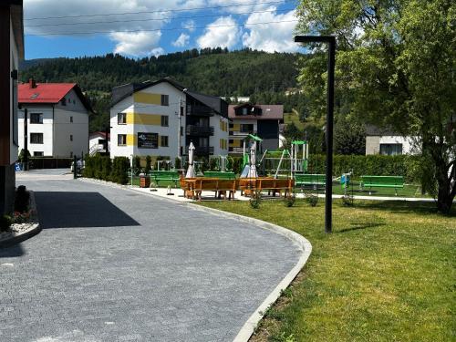 a street with a park with a playground and buildings at WRZOS resort & wellness in Węgierska Górka