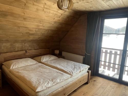 a bed in a wooden room with a window at Cabin House Čičmany- Relaxačné zariadenie s ubytovaním in Čičmany