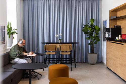 a man sitting at a table with a laptop at Fred Guest House Zürich Hauptbahnhof in Zürich