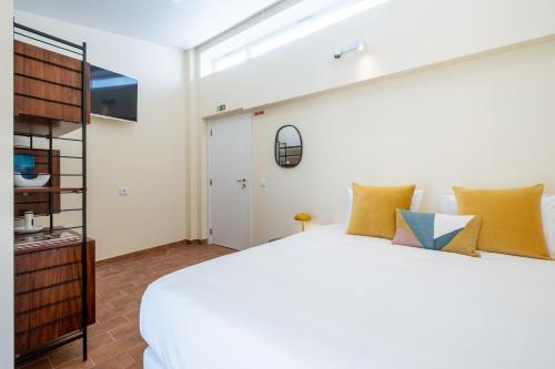 a bedroom with a large white bed with yellow pillows at CASASUPERTUBOS - Óbidos in Óbidos