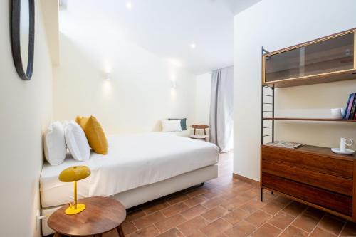 een slaapkamer met een wit bed en een houten dressoir bij CASASUPERTUBOS - Óbidos in Óbidos