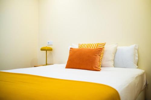 a bed with an orange pillow on top of it at CASASUPERTUBOS - Óbidos in Óbidos