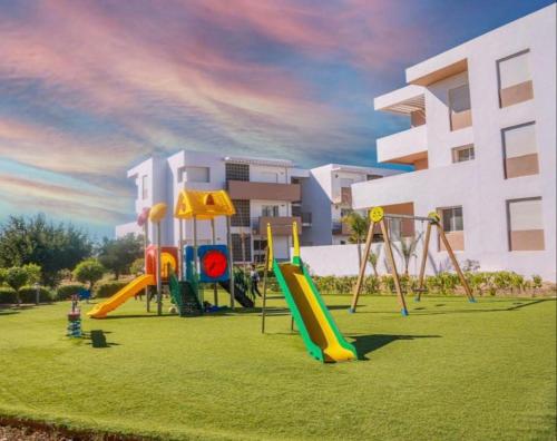 um parque infantil com um escorrega num campo de relva em Appartement Vue Sur Piscine Imi Ouaddar Taghazout em Agadir nʼ Aït Sa