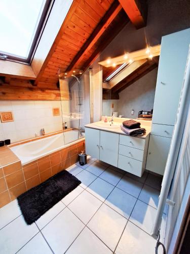 a large bathroom with a tub and a sink at L'appart du dessus - place de parking - wifi in Doubs