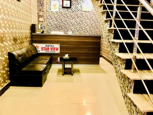 a lobby with a black leather couch and a stairway at Hotel New Star View in Bahawalpur