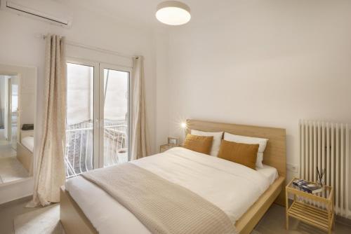a white bedroom with a large bed and a balcony at Kerameikou25 large in Athens