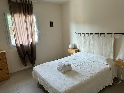 Un dormitorio con una cama blanca con una toalla encima. en Appartement avec piscine à 50 m de la plage, en Propriano