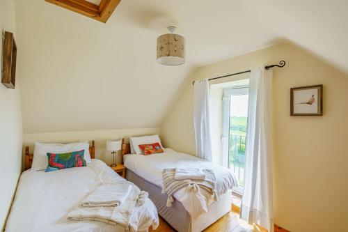 Duas camas num quarto com uma janela em The Steading at Castle Creavie Farm em Kirkcudbright