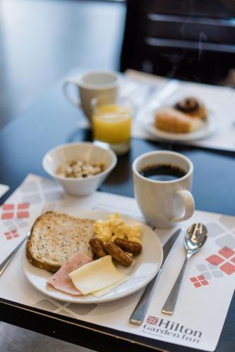 a tray with a plate of breakfast foods and a cup of coffee at Hilton Garden Inn Neuquen in Neuquén