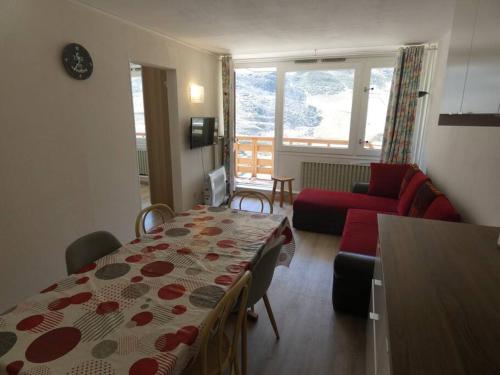 uma sala de estar com uma mesa e um sofá vermelho em Appart 4/6 pers La Mongie em Bagnères-de-Bigorre