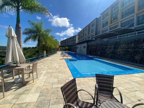 a swimming pool with chairs and an umbrella next to a building at Flat dos Sonhos Bananeiras in Bananeiras