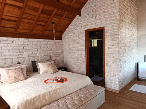 a bedroom with a large bed in a brick wall at Pousada rota nas montanhas in Camanducaia