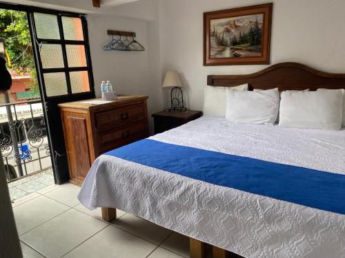 a bedroom with a blue and white bed and a balcony at Hotel Nacional in Oaxaca City