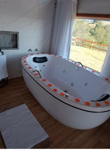 a large white bath tub in a room with a window at Pousada rota nas montanhas in Camanducaia