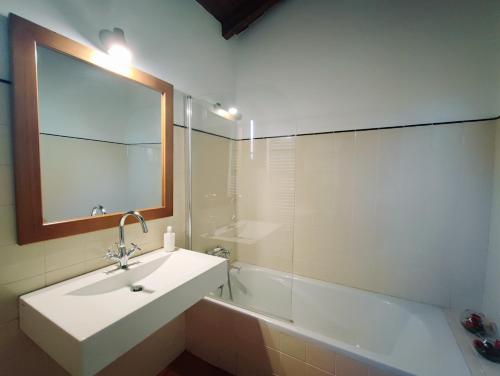 a bathroom with a sink and a tub and a mirror at Casa das Falagueiras in Castro Laboreiro