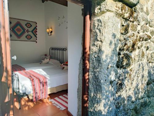 a bedroom with a bed and a stone wall at Casa das Falagueiras in Castro Laboreiro