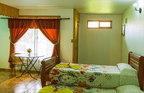 Habitación con 2 camas, mesa y ventana en Hostal y Cabañas Aorangi, en Hanga Roa