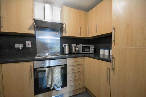 eine Küche mit Holzschränken und einem Herd mit Backofen in der Unterkunft 2 Bedroom 2 Bathroom Free Parking Nearby in Manchester