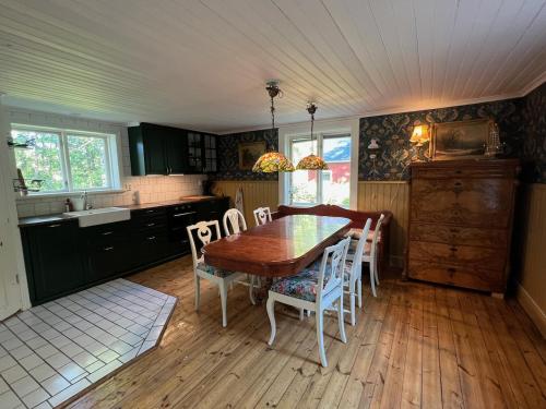 uma cozinha com uma mesa de jantar em madeira e cadeiras em Drömtorp med egen brygga em Östhammar