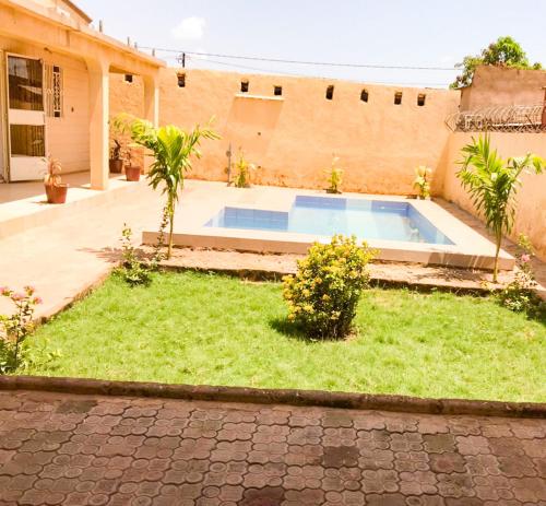 a yard with a swimming pool in front of a house at Résidences KZOTOOL Ouaga in Ouagadougou
