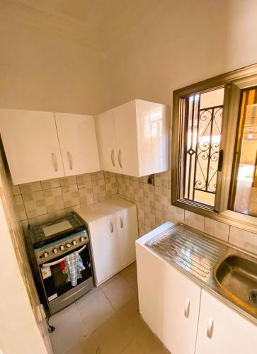 a small kitchen with a stove and a window at Résidences KZOTOOL Ouaga in Ouagadougou