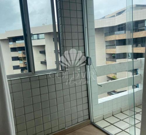 una puerta de ducha de cristal con vistas a un edificio en Apartamento Cotê D'Azur à beira-mar., en Maceió