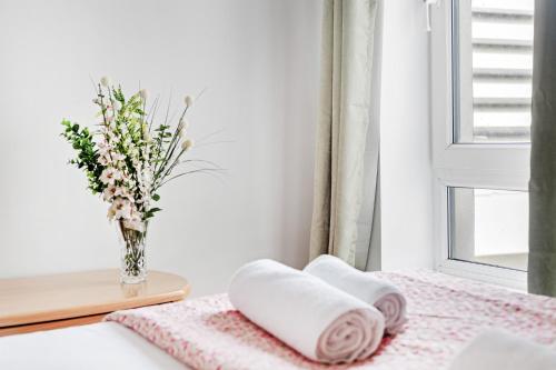 a bedroom with two towels and a vase with flowers at 2 Bed Waterfront Apartment, 3 Minutes From Train Station in Nottingham