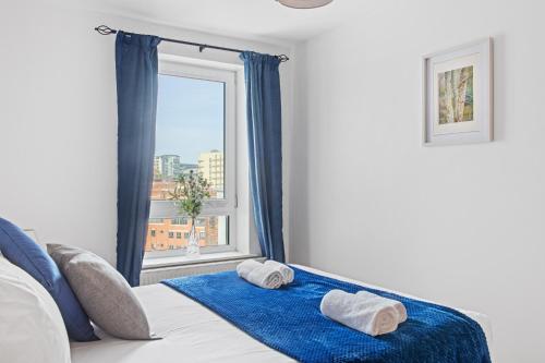 1 dormitorio con ventana y toallas en la cama en 2 Bed Waterfront Apartment, 3 Minutes From Train Station en Nottingham