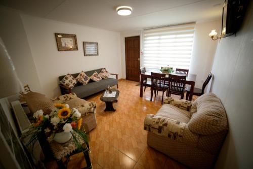 a living room with a couch and chairs and a table at Departamentos Cordillera in Punta Arenas