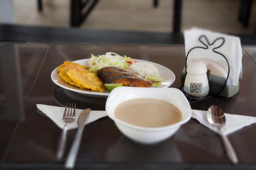 a table with a plate of food and a cup of coffee at Caribbean Town Tolu in Tolú