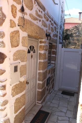 a stone house with a white door and a wall at Casa da Avó Carriça in Santar