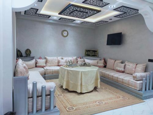 uma sala de estar com uma mesa e sofás e uma televisão em Appartement de luxe à 7 min de Centre de ville em Marrakech