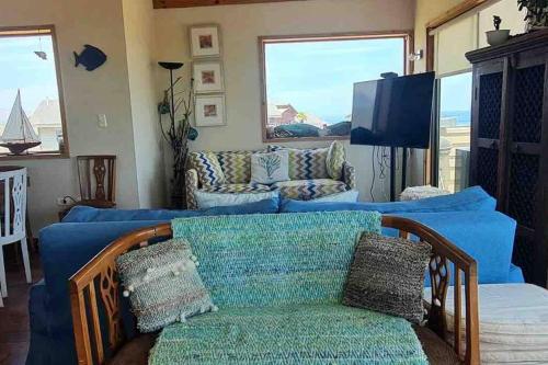 uma sala de estar com um sofá azul e uma televisão em Pichidangui Comoda Casa Vista al Mar Full Equipada em Pichidangui