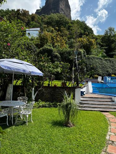 un patio con una mesa y una sombrilla en el césped en BUNGALOWS ANDREA, en Tepoztlán