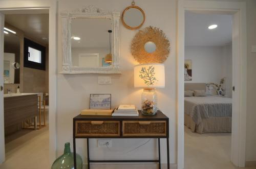 Habitación con mesa, cama y espejo. en Los Flamencos EXCELLENT & SOLMARES, en Isla Canela