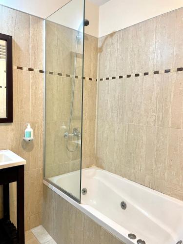 a bathroom with a tub and a glass shower at Complejo Hermogenes in San Juan