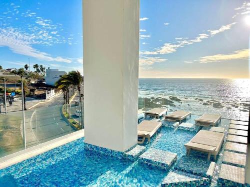 a pool with chairs and a view of the ocean at Boca de cielo 504 / Vista al mar in Mazatlán