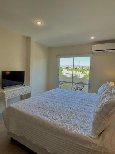 a bedroom with a bed and a desk and a television at Complejo Hermogenes in San Juan