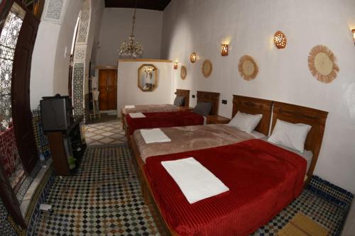 um quarto com duas camas e uma televisão em hostel Dar belghiti em Fez