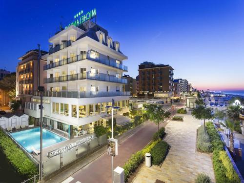 un hôtel avec une piscine en face d'un bâtiment dans l'établissement Hotel Michelangelo, à Riccione