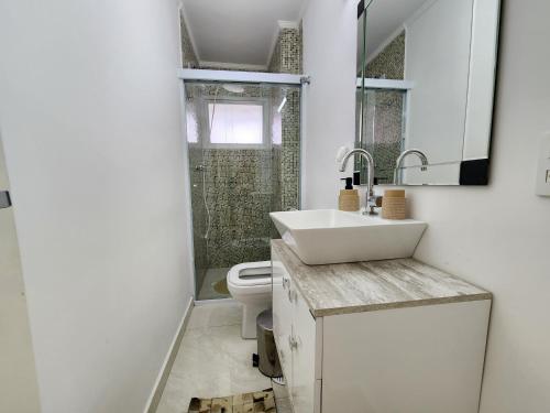 uma casa de banho com um lavatório e um WC em Lindo apartamento3 quartos Enseada 8 pessoas no Guarujá