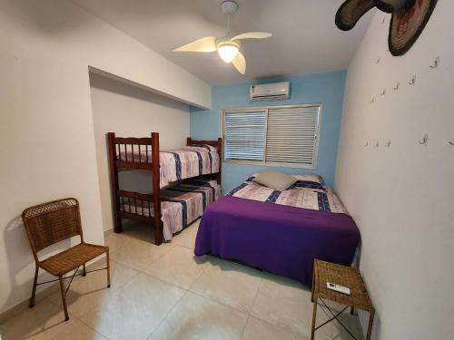 um quarto com 2 camas individuais e uma cadeira em Lindo apartamento3 quartos Enseada 8 pessoas no Guarujá