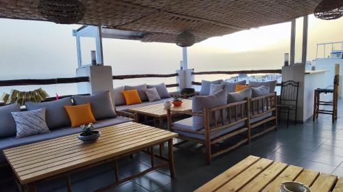 un restaurante con sofás y mesas en un balcón en BigBlue Hostel - Taghazout, en Taghazout