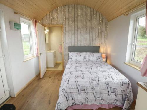 Tempat tidur dalam kamar di The Lazy Llama Farm Stay Shepherd Hut