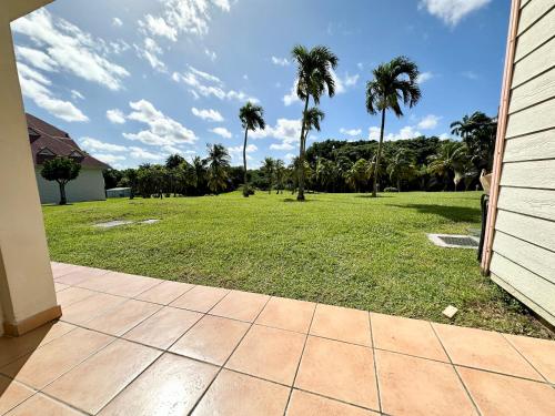 a yard with palm trees and a field of grass at Studio dans un magnifique complexe de vacances a ST luce in Sainte-Luce