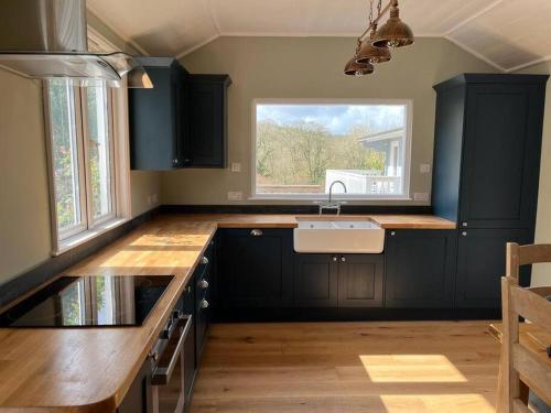 cocina con armarios negros, fregadero y ventana en Lower Hill Cottage w/Swedish Hot Tub en Bodmin