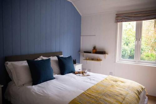 a bedroom with a bed with blue walls and a window at Lower Hill Cottage w/Swedish Hot Tub in Bodmin