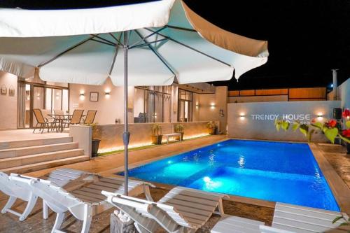 uma piscina com cadeiras brancas e um guarda-sol em Trendy house -deadsea em Al Rama