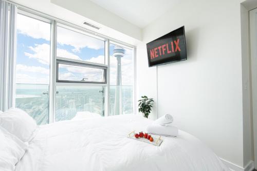 um quarto com uma cama branca e uma televisão na parede em Beautiful Luxurious Modern Condo With Breathtaking Views em Toronto