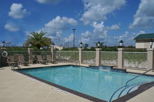 a swimming pool at a resort with chairs and a fence at Hampton Inn Orange in Orange